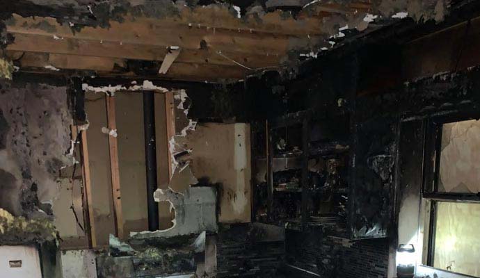 Fire-damaged interior space Interior space severely affected by fire, showing burn marks, soot and structural damage
