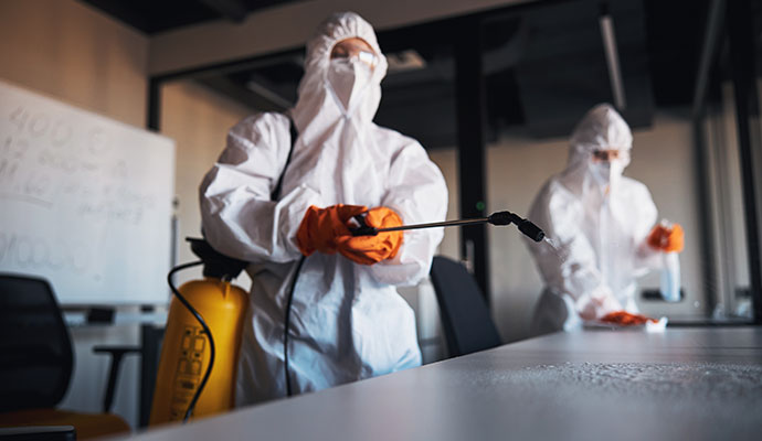 Disinfection specialists in hazmat suits and orange gloves