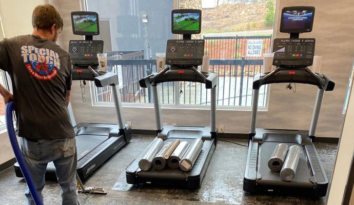 Professional cleaner mopping and polishing the gym floor for a spotless finish.