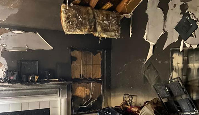 Severe residential fire damage with charred walls and ceiling insulation