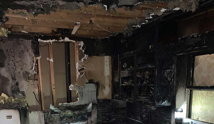 Severely fire-damaged room including collapsed structure and ruined furnishings.