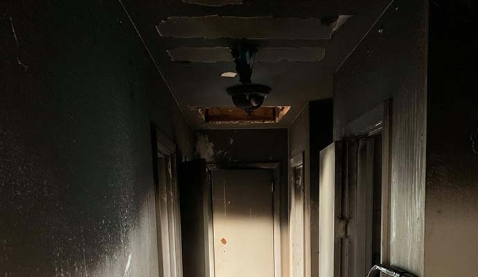 Walls and ceiling covered with black soot and smoke stains after a house fire.