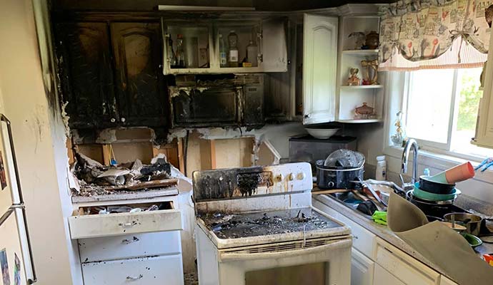 Burned kitchen interior with smoke stains and charred cabinets after a house fire.