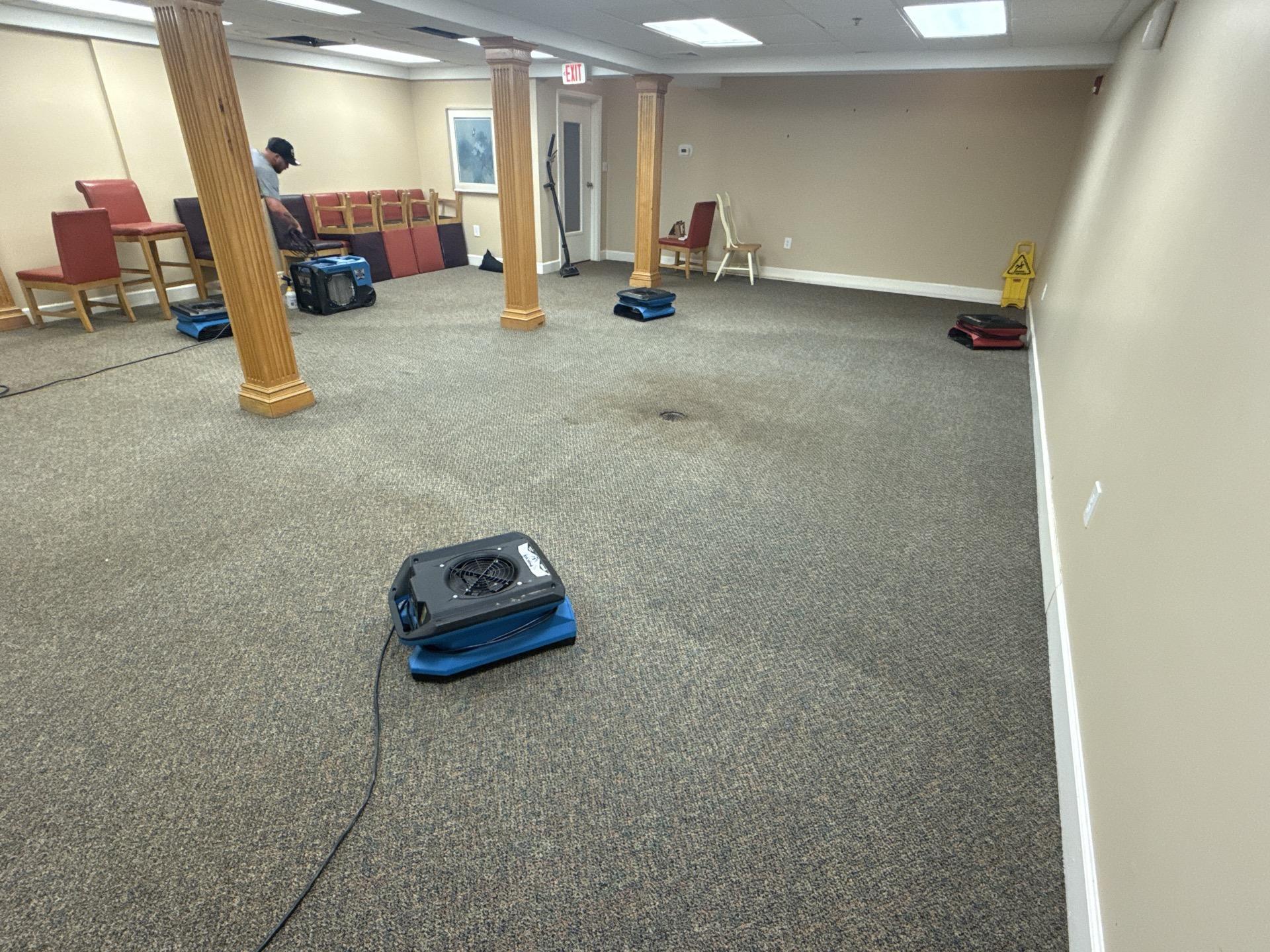 Professional drying equipment deployed in a community room after significant flooding from a burst drain line. Special Touch Restoration provides rapid flood mitigation services.