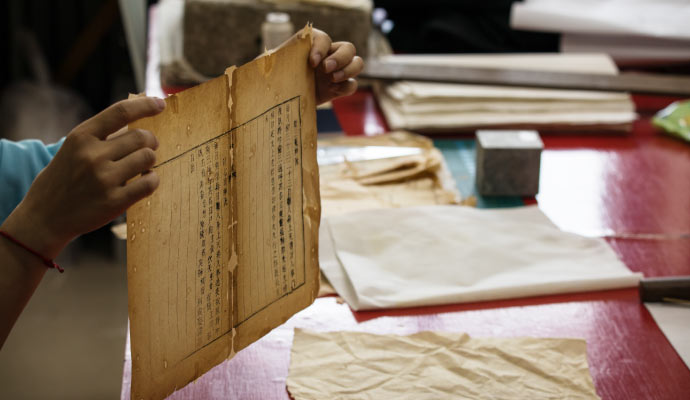 An expert holding a damaged paper document for restoration
