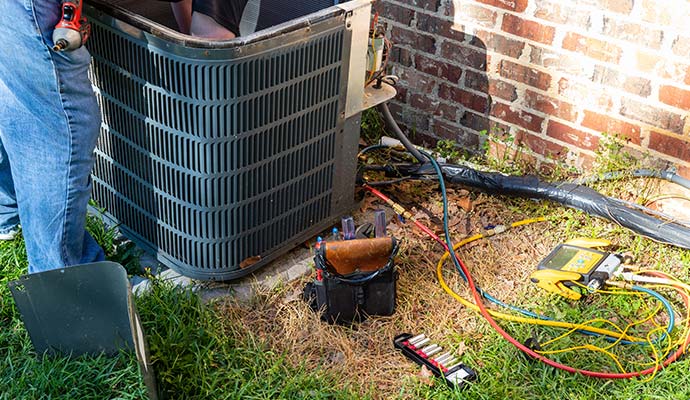 Technician performing maintenance on an outdoor air conditioning unit.