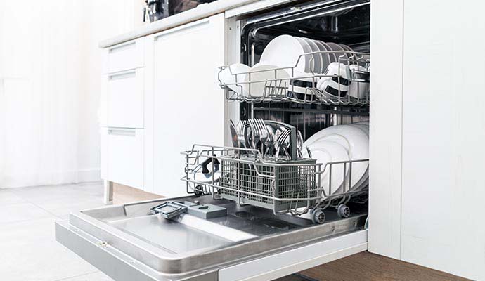 Open dishwasher with neatly arranged dishes Open dishwasher loaded with clean and neatly arranged dishes